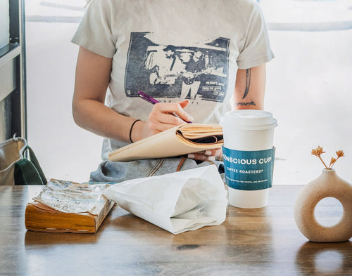 Girl enjoying a latte while reading and journaling.