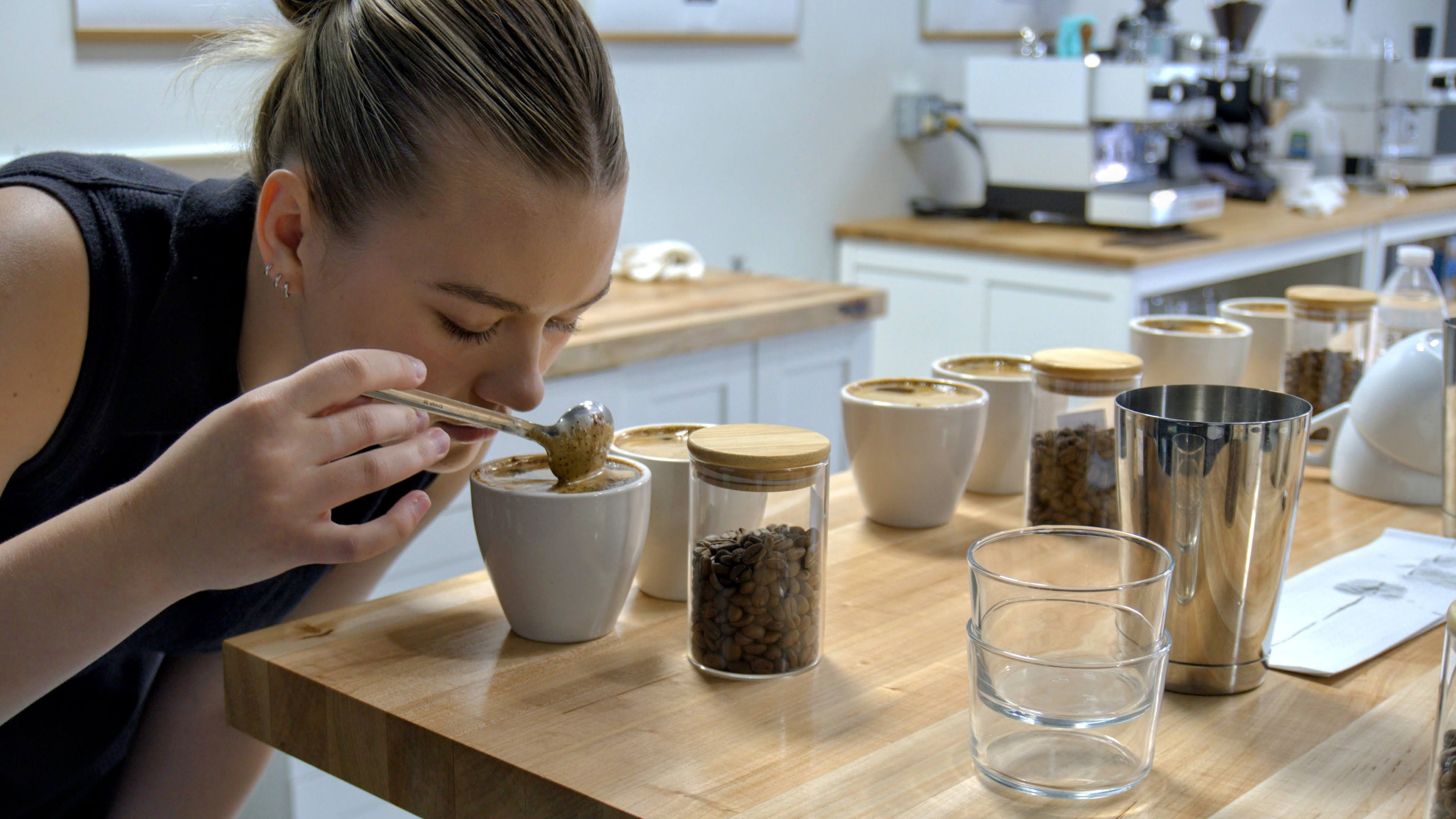 A girl takes a whiff of coffee at a coffee cupping event