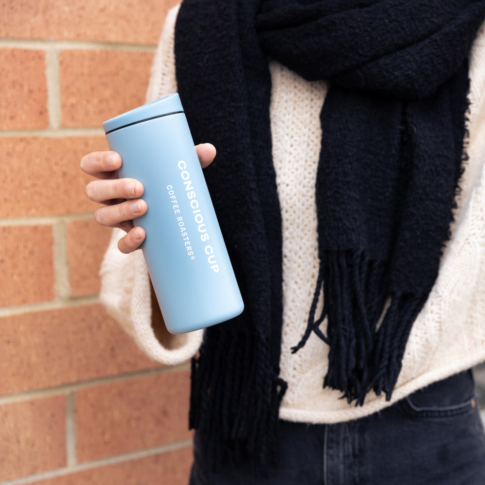 Person holds a Conscious Cup Coffee traveler cup